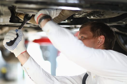 Auto mechanic checks running gear of car at service station. Car mechanic fixing problem with car and problem solving concept