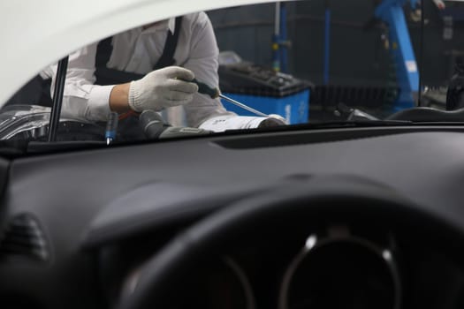 Mechanic checks engine and cooling system in car workshop. Auto repair and maintenance concept