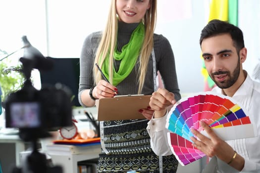 Fashion designers woman and man chooses color from a palette to camera. Creative workspace with color swatches and offline designer fashion blog