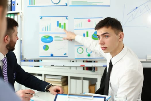 Smiling business team working with financial analytics in charts on white board. Seminar marketing and training statistics concept