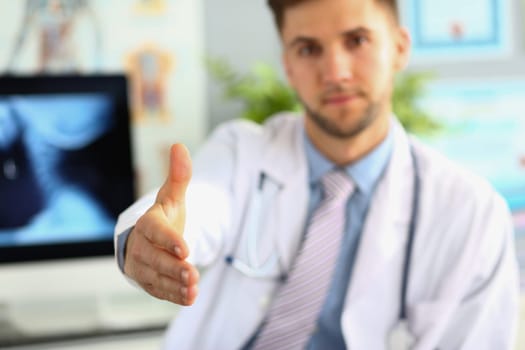 Closeup of male doctor offering handshake in office. Welcome gesture and health insurance concept