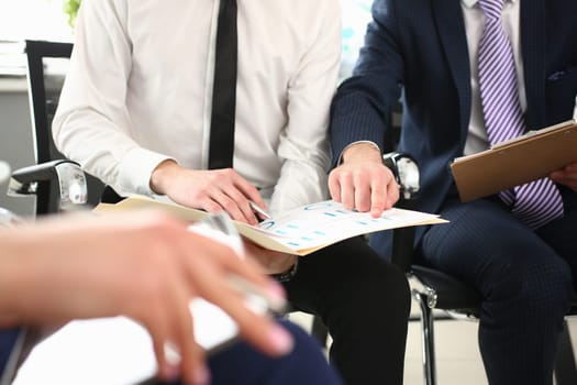 Closeup table of statistics shown on charts and hands of different businessmen. Collaborative team work team leader and explaining financial result of project