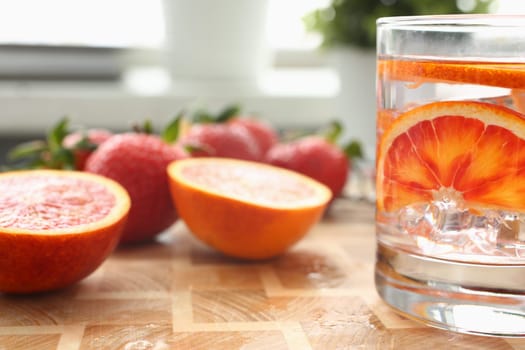 Red orange punch with strawberry and orange in glass with ice. Homemade chilled alcoholic cocktail closeup