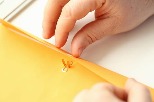 Closeup of business person opening yellow envelope with business mail. Business correspondence and documentation concept