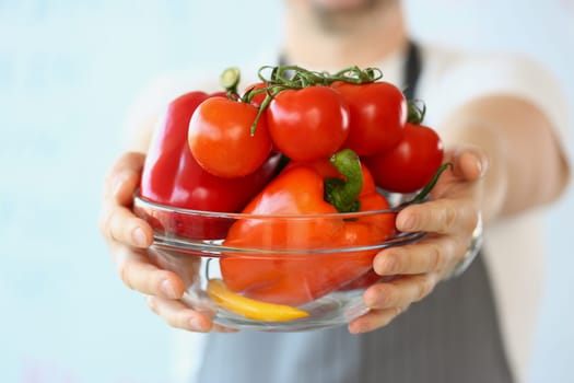 Hand of cook holds large plate with various vegetables. Organic healthy vegetable food concept