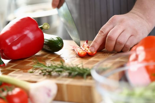 Chef cuts chili peppers on board closeup. Cooking vegetables and vegan food with spices concept