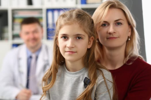 Portrait of mother and daughter on background of pediatrician medical doctor. Medical examination and family insurance concept