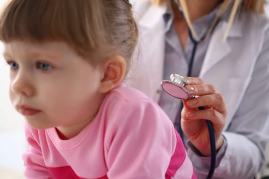 Pediatrician listens to lungs of little girl with stethoscope. Pediatrics medical services and child insurance concept