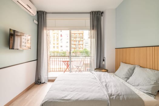 Spacious bright room with bed, large opening on entire wall with sliding plastic doors and access to balcony. Room has table with chair, air conditioning and TV for pleasant leisure