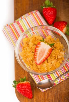 Bowl of tasty crispy corn flakes with milk and strawberries on white