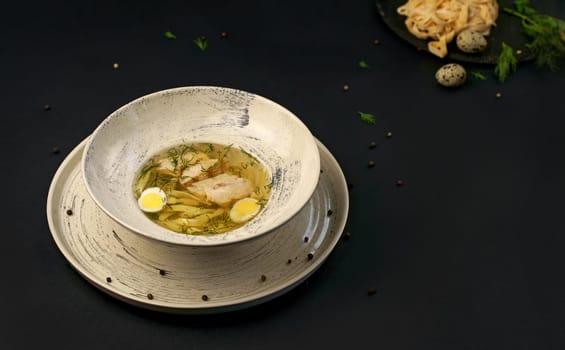 chicken soup with vermicelli and vegetables close-up in a bowl on a wooden tray on the table.