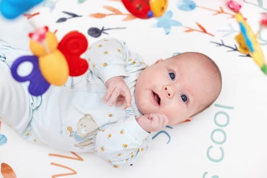 smiling cute newborn baby in crib with toys at home