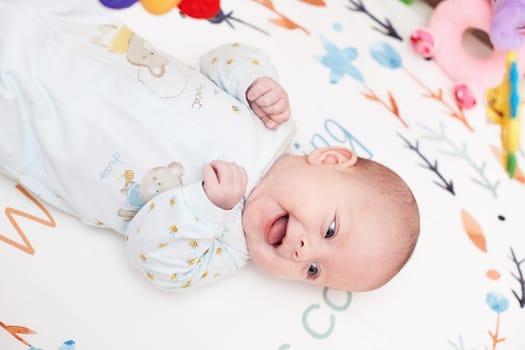 smiling cute newborn baby in crib with toys at home