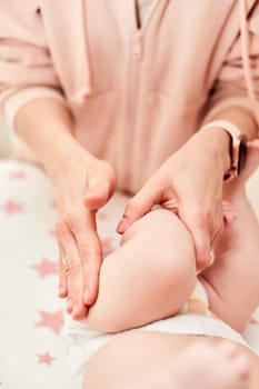 Mom or therapist giving massage to baby at home. massage of baby legs by mother.