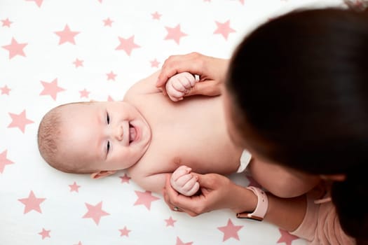 Loving mother playing with baby girl. top view. Mom giving massage to child