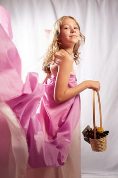 Portrait of cute kid girl posing in pink beautiful dress on white background. Model in studio looking as gentle magic princess from fairy taly having photo shoot on white background