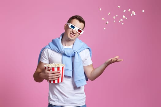 indignant man in 3d glasses, white t-shirt with flying popcorn on pink background. What do you want
