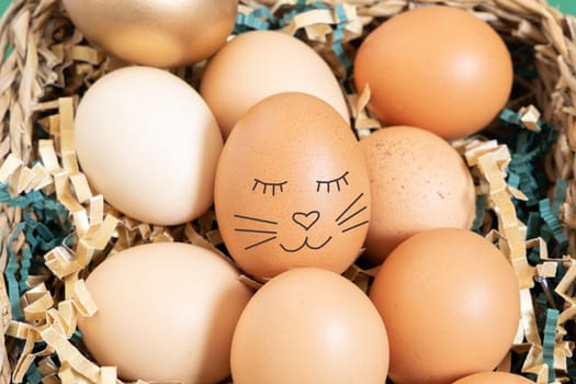 Close up of easter eggs with funny bunny face natural and gold in basket with paper filler.