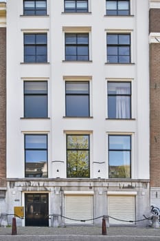 Amsterdam, Netherlands - 10 April, 2021: a building with windows and bicycles parked on the sidewalk in front of it's doors, next to a fire hydrator