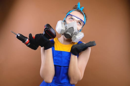 Young insecure worker, handyman, woman in a t-shirt, glasses, holding a drill on a plain background. Tools, accessories for the repair room. Home renovation concept.