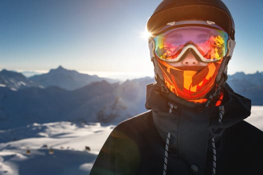 Portrait of a woman in the Alps. A young woman, a snowboarder or a skier in a snowy winter on a mountain slope, her beautiful happy eyes are visible through a ski mask or goggles.
