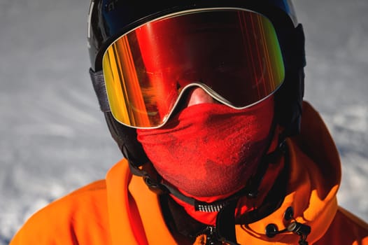 Portrait of a snowboarder. Ski goggles and ski helmet on a man looking at the camera, close-up. Holidays in the ski resort.