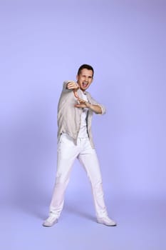 optimistic caucasian young man pointing finger on camera on pastel violet background. Full body