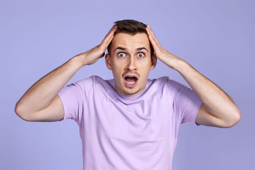 shocked man with surprise expression, fear and excited face on pastel purple studio background