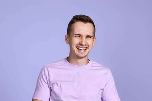 positive handsome man smiling on pastel purple studio background