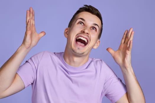 annoyed angry man in furious gesture on pastel purple studio background