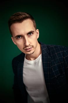 portrait of handsome man in plaid jacket looking at camera on green background.