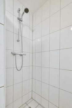 a bathroom with white tiles on the wall and shower head mounted to the wall in front of the bathtub