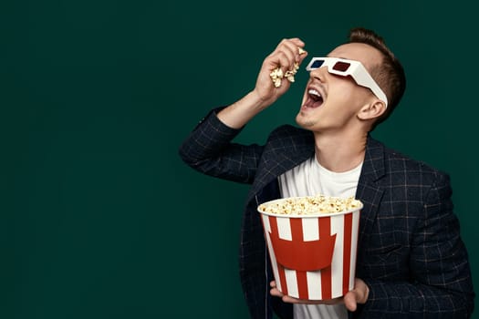 handsome man in 3d glasses and plaid jacket eating popcorn on green background. copy space