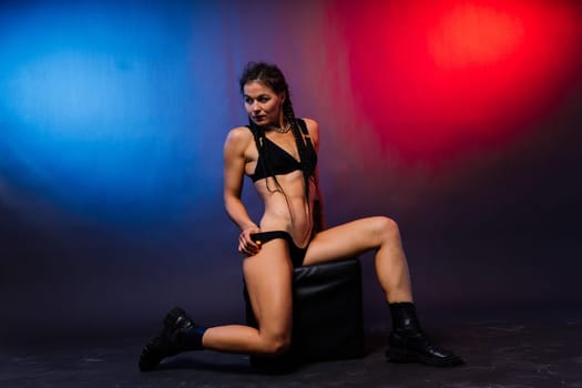 Beautiful female body on dark background in a red blue neon light. Fit and sportive, sensual.