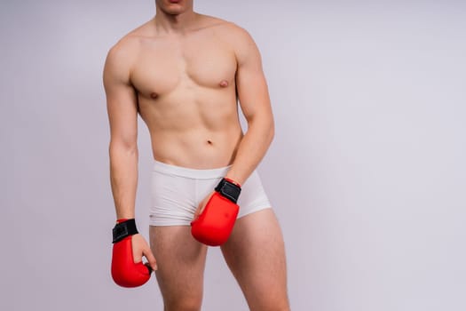 Bodybuilders boxing gloves on a white background and white pants athlete model