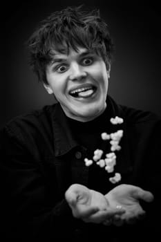 portrait of crazy young man throwing up popcorn and grimacing . black and white