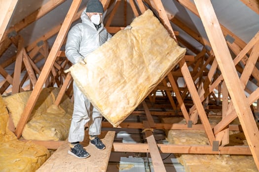 a worker in protective overalls works with glass wool. High quality photo