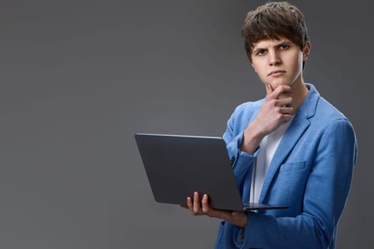 caucasian young man in blue jacket using laptop computer for online work isolated on gray background