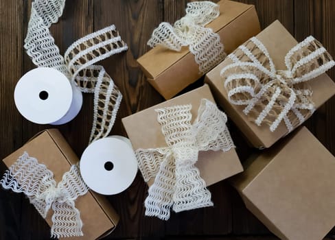 On a wooden table there are craft boxes decorated with bows. Handiwork. Handmade work. The use of recycled paper.