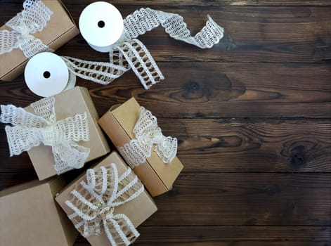 On a wooden table there are craft boxes decorated with bows. Handiwork. Handmade work. The use of recycled paper.