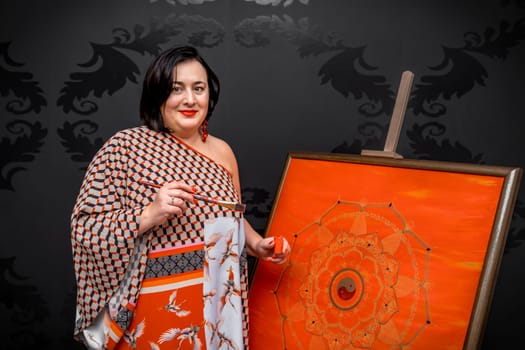 the artist draws a mandala with a brush and red paint on the canvas. High quality photo