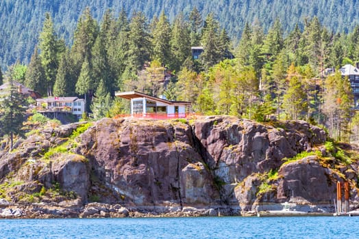 Rocky shore of the Pacific ocean in Vancouver. Residential house under contstruction at the waterfront