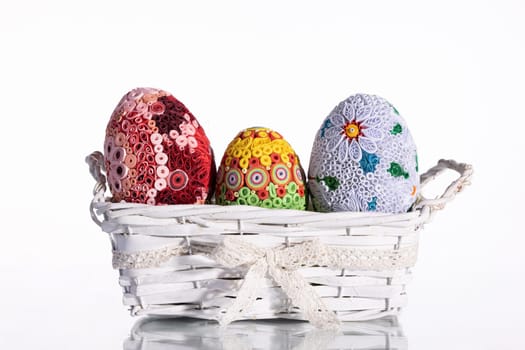 Isolated behind the background a woven basket with three Easter eggs. Important symbols of the world in the Christian religion.