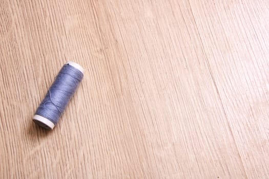 Coil of grey thread on a wooden table close up