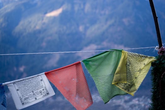 sacred religious multicolored prayer flags on fence moving in the wind showing a bhuddist prayer incantation common in hill stations in Himachal Pradesh India