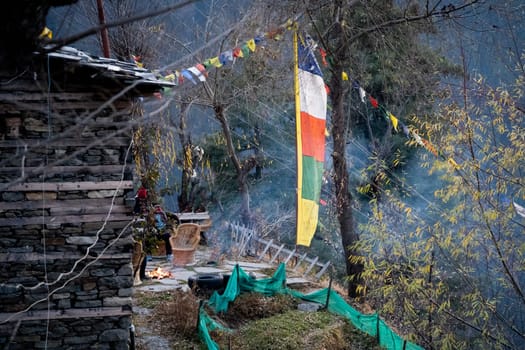 sacred religious multicolored prayer flags old and tattered torn outside wooden cabin in bhuddist prayer incantation common in hill stations in Himachal Pradesh India