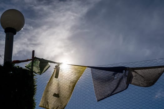 religious multicolored prayer flags old and tattered torn moving in the wind showing a bhuddist prayer incantation common in hill stations in Himachal Pradesh India