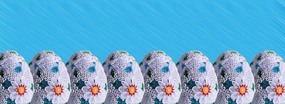 Many Easter eggs lined up one next to the other and the whole composition is set against a solid blue background.