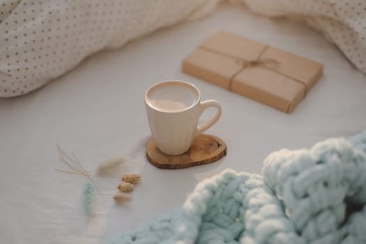Light cozy bedroom, Coffee cup and gift or book on the bed. Good morning