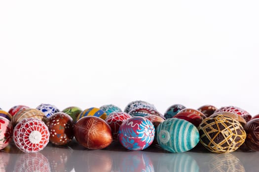 Composition of Easter eggs set in a row on a solid white background. The set Easter decoration is reflected in the glass.